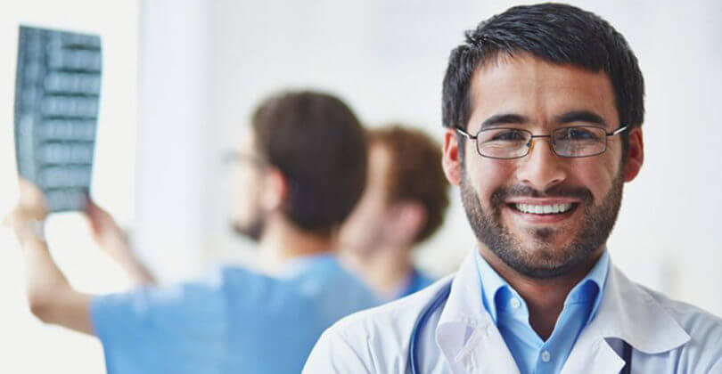 Picture of a doctor, representing all doctors in San Jose, Costa Rica.  The picture is a close-up picture of a male doctor with a stethoscope around his neck, smiling at the camera.